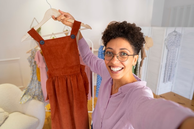 Free Photo smiley woman presenting clothes high angle