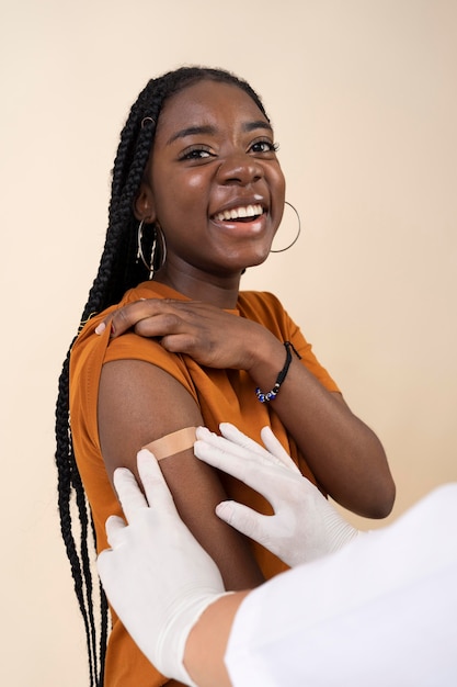 Smiley woman receiving sticker on arm after getting a vaccine