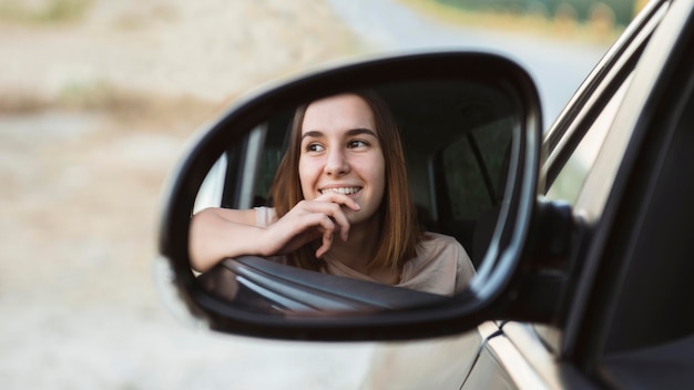 Smiley woman's reflection in car's mirror