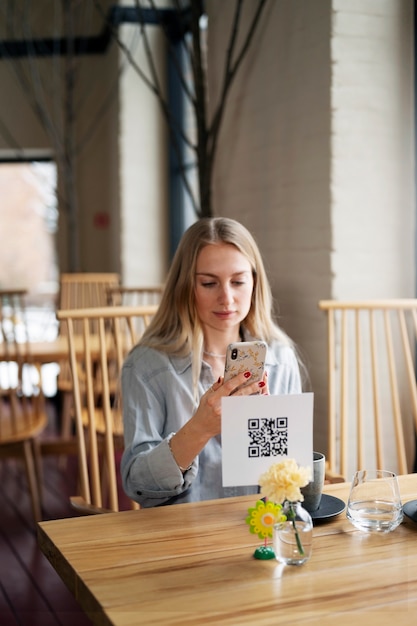 Free Photo smiley woman scanning qr code at restaurant