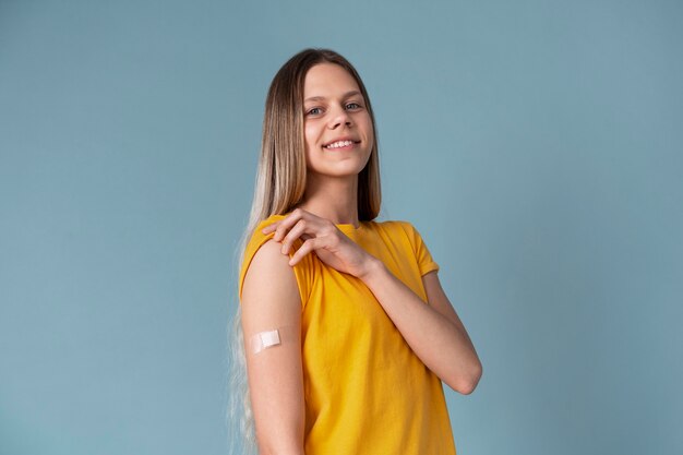 Smiley woman showing arm with sticker after getting a vaccine