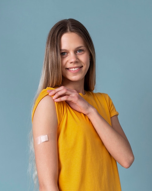 Smiley woman showing arm with sticker after getting a vaccine