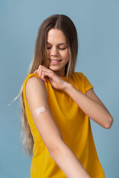 Free Photo smiley woman showing arm with sticker after getting a vaccine