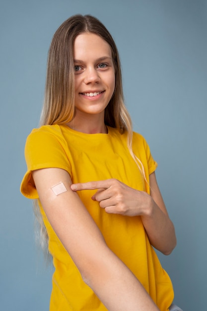 Smiley woman showing arm with sticker after getting a vaccine