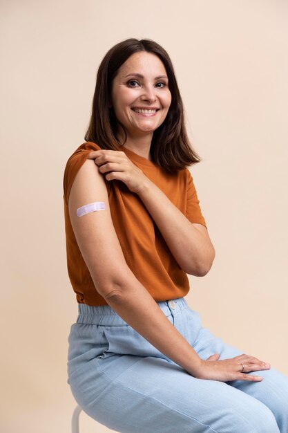 Smiley woman showing sticker on arm after getting a vaccine