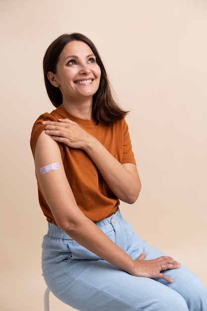 Smiley woman showing sticker on arm after getting a vaccine