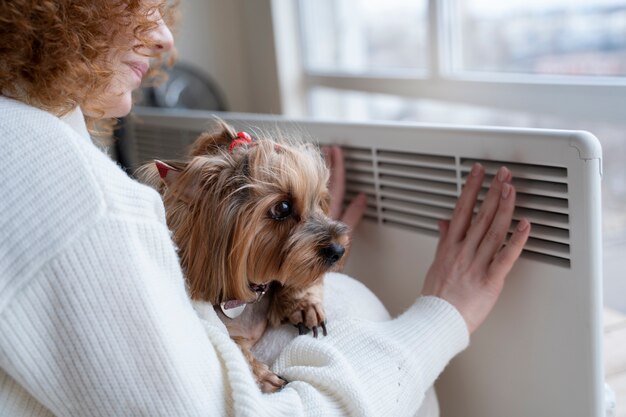 Smiley woman sitting near heater with dog