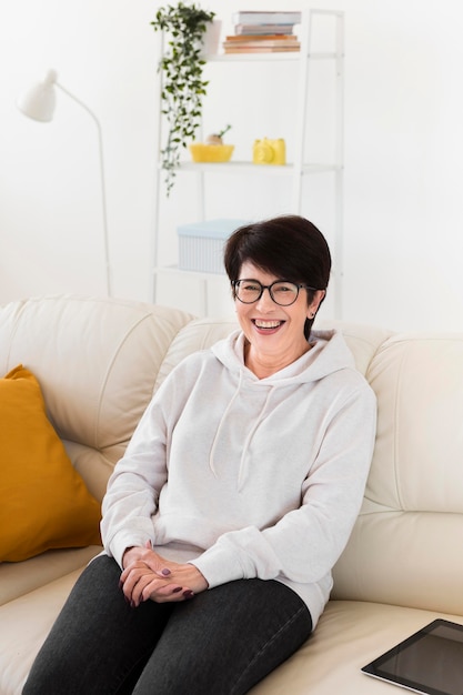 Smiley woman on sofa at home with tablet