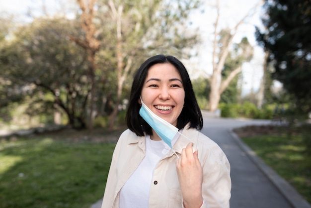 Smiley woman taking mask off medium shot