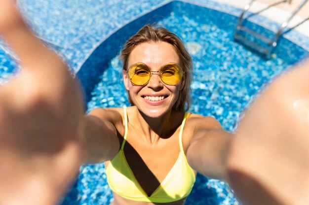 Smiley woman taking selfie at pool