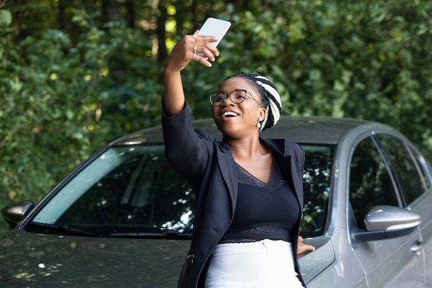 Smiley woman taking a selfie with her brand new car