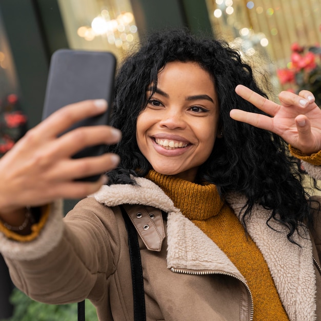 Free Photo smiley woman taking a selfie with her smartphone outdoors