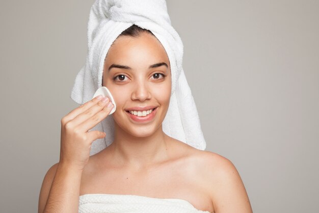 Smiley woman using a cotton pad on her face