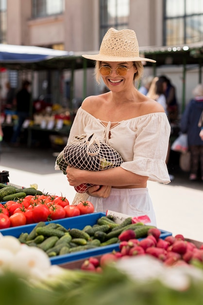 Free photo smiley woman using organic bag for veggies