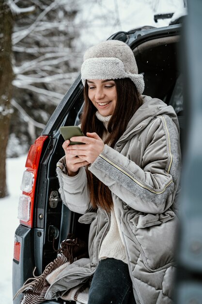 Smiley woman using smartphone from the car while on a road trip