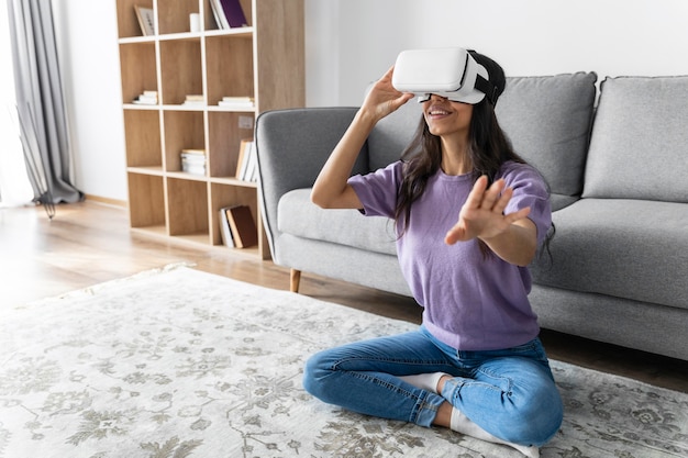 Free photo smiley woman using virtual reality headset at home