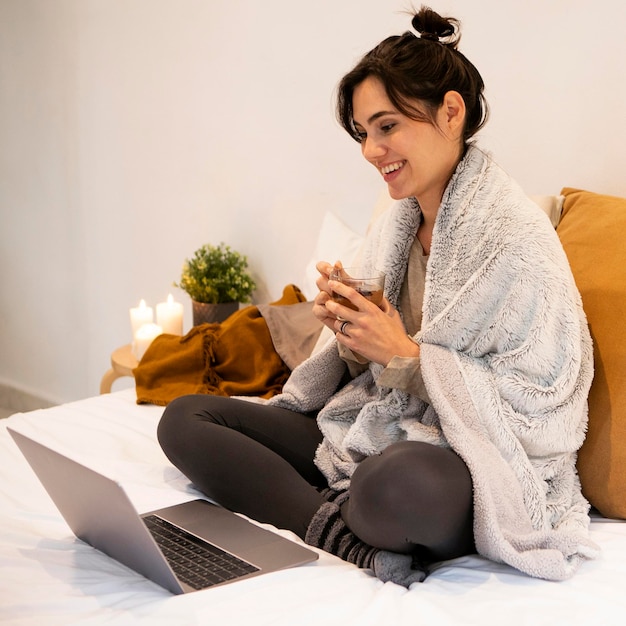 Free photo smiley woman watching a tv show on the laptop