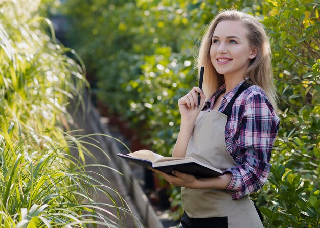 Smiley woman with agenda in greenhouse