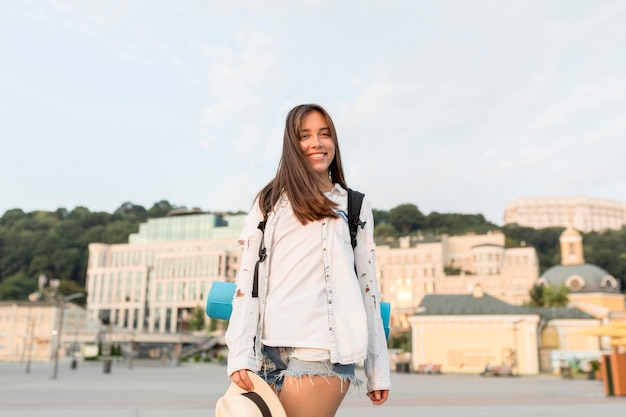 Smiley woman with backpack and hat posing while traveling