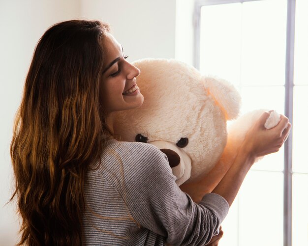 Smiley woman with big teddy bear at home