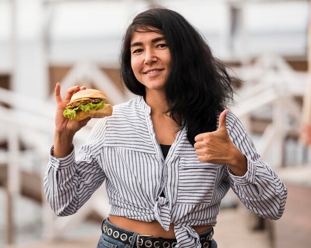 Smiley woman with burger showing approval