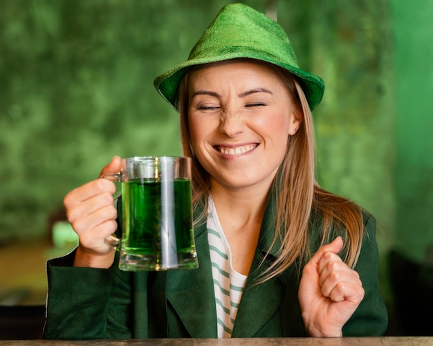 Smiley woman with hat celebrating st. patrick's day with drink