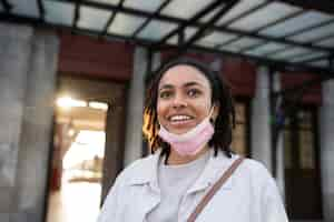 Free photo smiley woman with pink mask low angle