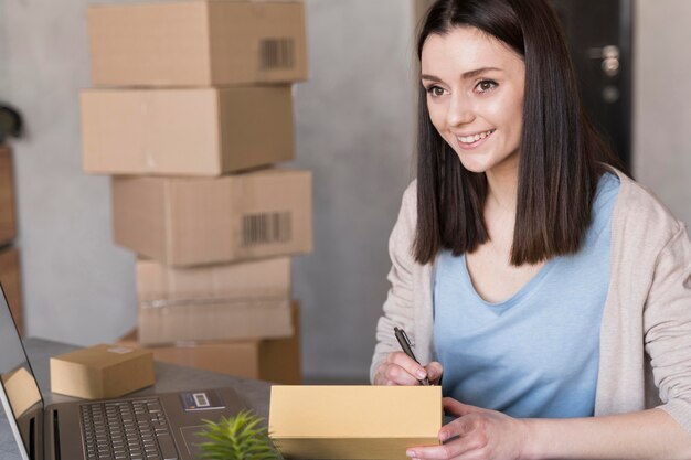 Smiley woman writing something next to laptop