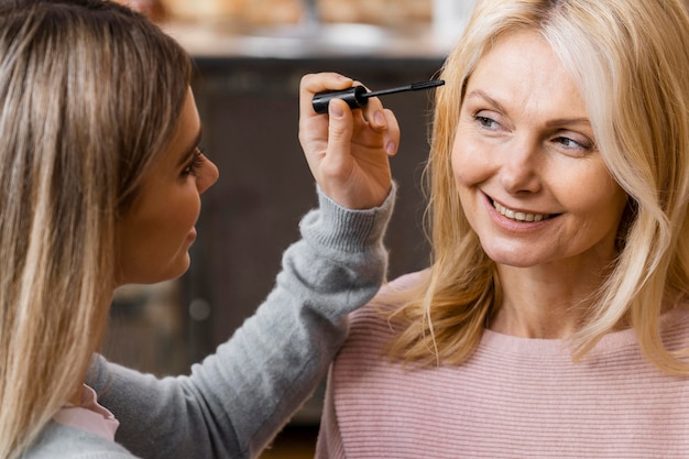 Free photo smiley women using mascara at home