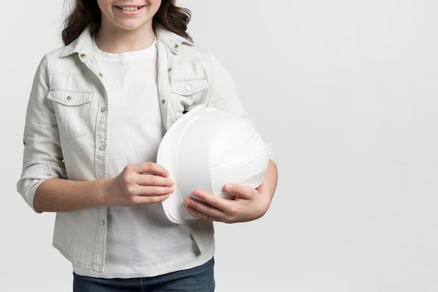 Free Photo smiley young girl holding hard hat with copy space