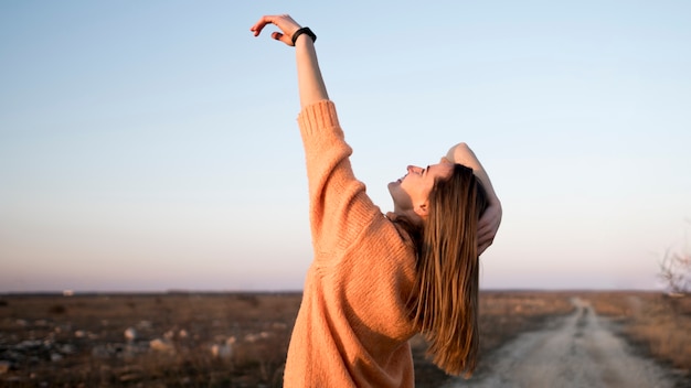 Free photo smiley young girl on the road with her hand in the air