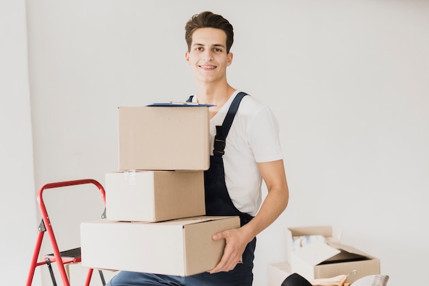 Smiley young man holding carton boxes