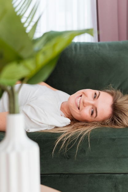 Free photo smiley young woman relaxing at home and plant