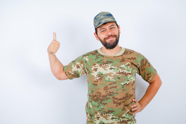 Smilig soldier is showing perfect gesture and putting other on waist on white background