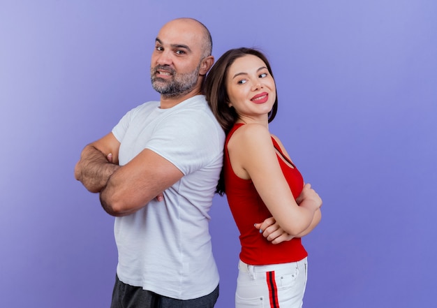 Smiling adult couple standing with closed posture in profile view back to back 