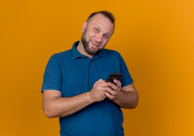 Smiling adult slavic man holding mobile phone looking 