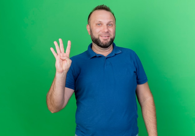 Smiling adult slavic man showing four with hand isolated on green wall with copy space