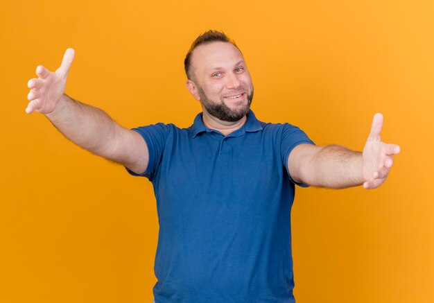 Smiling adult slavic man stretching out hands towards isolated