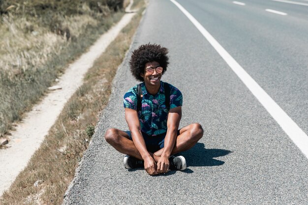 Smiling African American man sitting on road