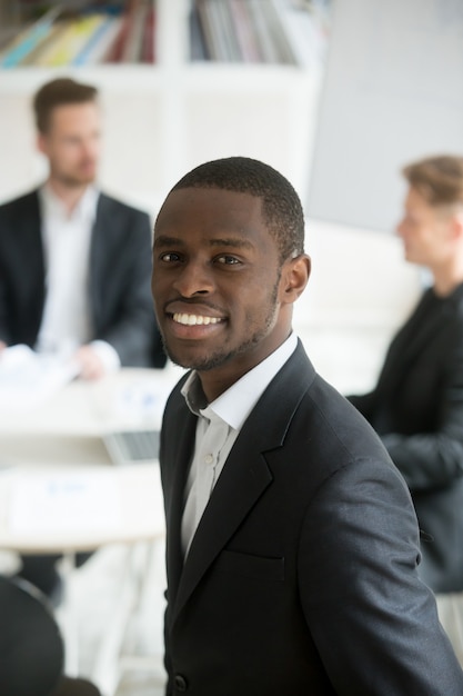 Free photo smiling african businessman wearing suit headshot vertical portrait with team