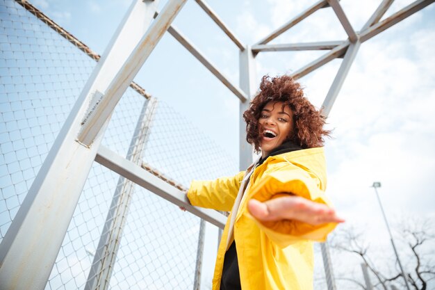 Smiling african curly young lady wearing yellow coat