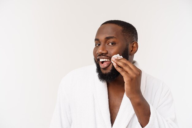 Smiling african man apply cleansing his face mans skin care concept