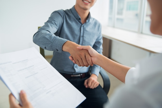 Smiling Asian businessman shaking partners hand