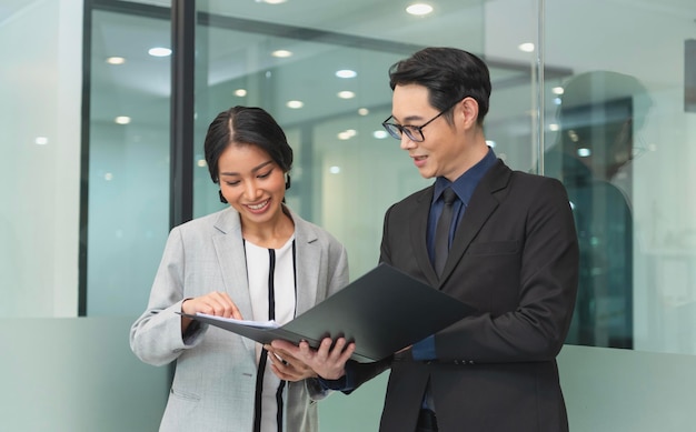 Smiling asian businesswoman showing document report to her manager during a meeting in the office