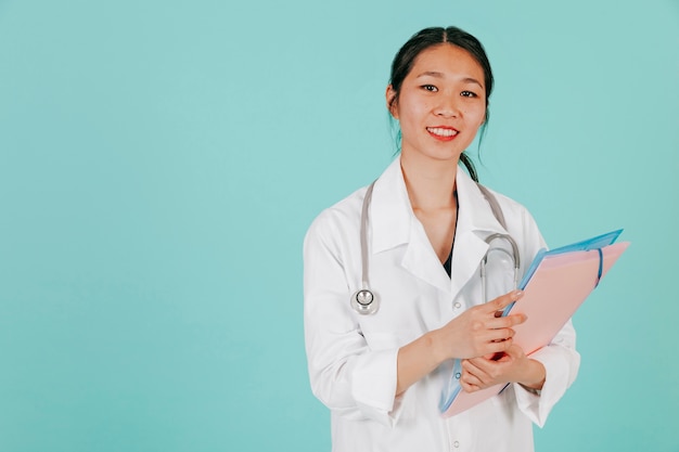 Free photo smiling asian doctor with stethoscope and folder