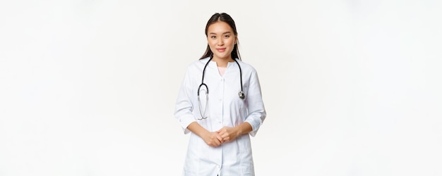 Free photo smiling asian medical worker with stethoscope wearing doctor uniform looking helpful at patient stan