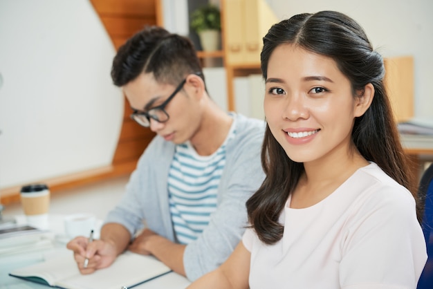 Smiling Asian woman with male colleague at table