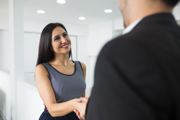 Smiling attractive businesswoman making handshake with partner