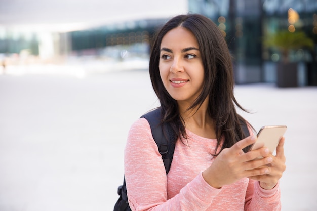 Smiling attractive young woman texting sms on phone