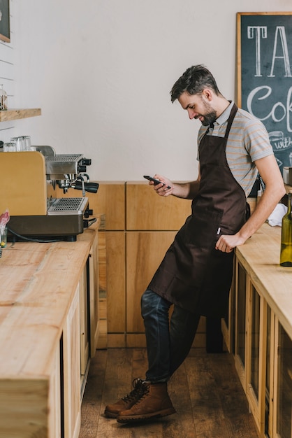 Free photo smiling barista using smartphone